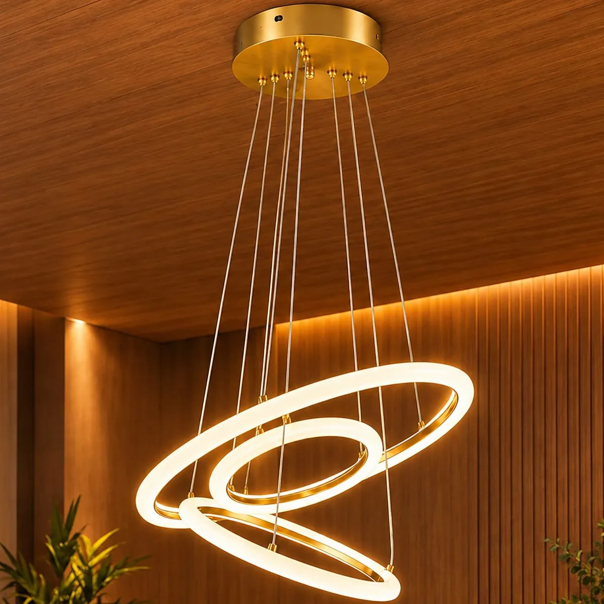 Pendente de três anéis LED dourados aceso sobre mesa de jantar, em sala com painéis de madeira